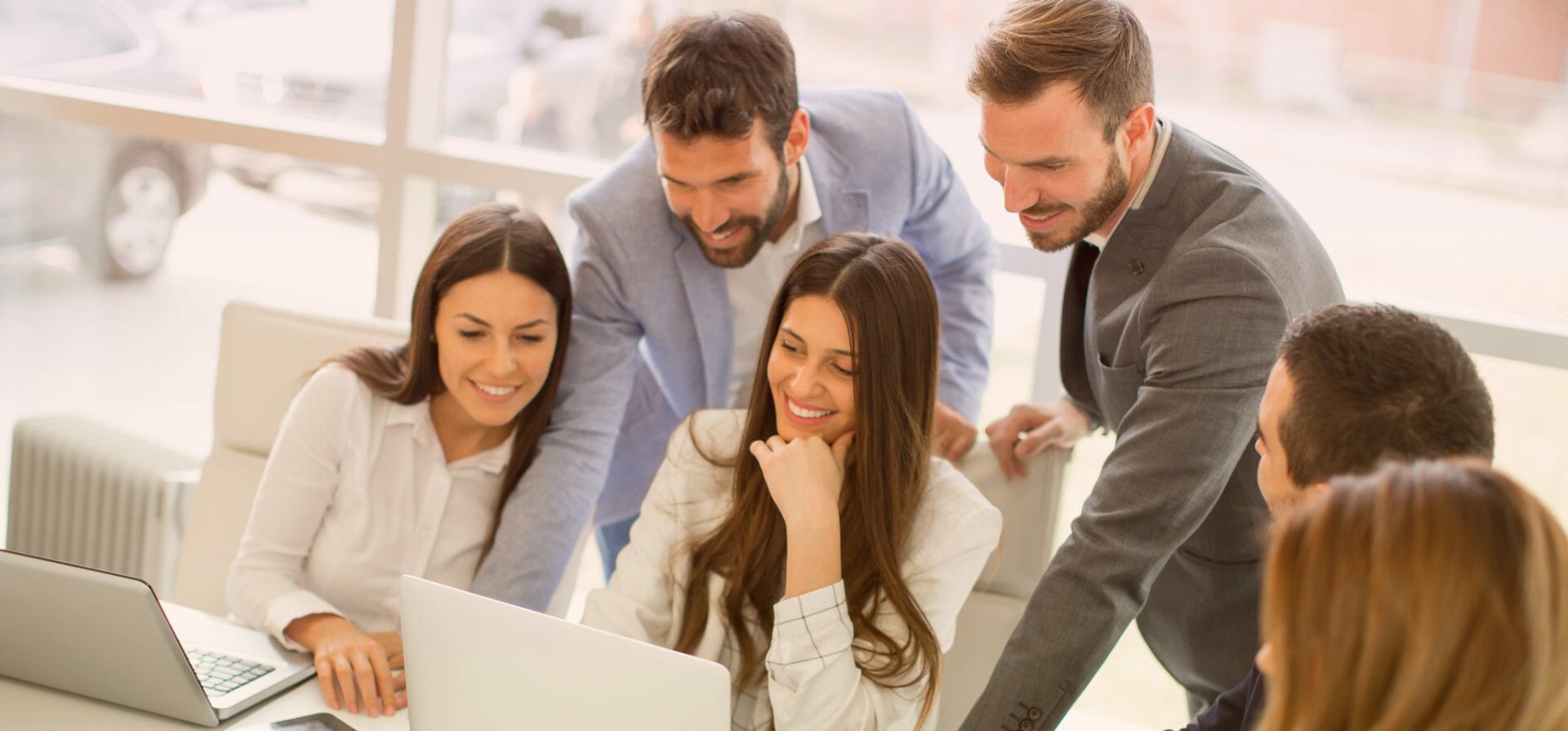 Eine Gruppe von Menschen, die um einen Laptop stehen, um Wissen auszutauschen.