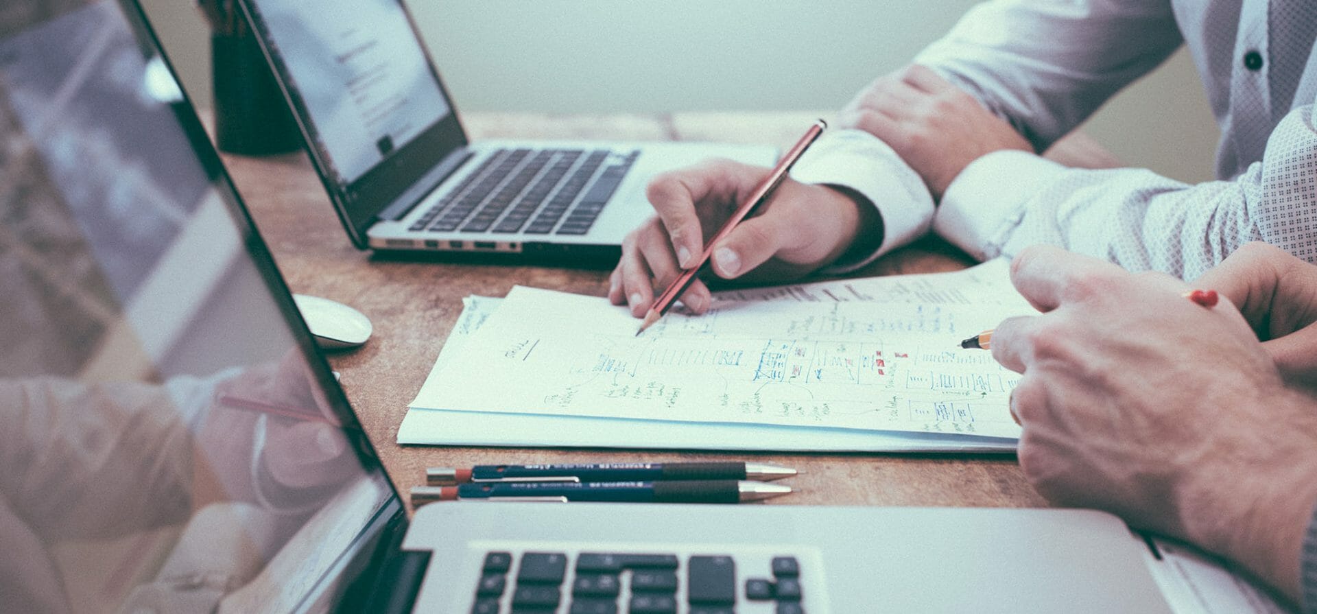 Deux personnes en formation dans un environnement d'entreprise, collaborant avec des ordinateurs portables, des feuilles et des stylos.