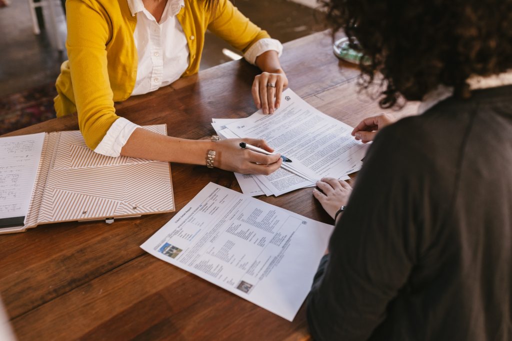 Twee personen die deelnemen aan een zakelijk trainingsprogramma, zittend aan een tafel met papierwerk.