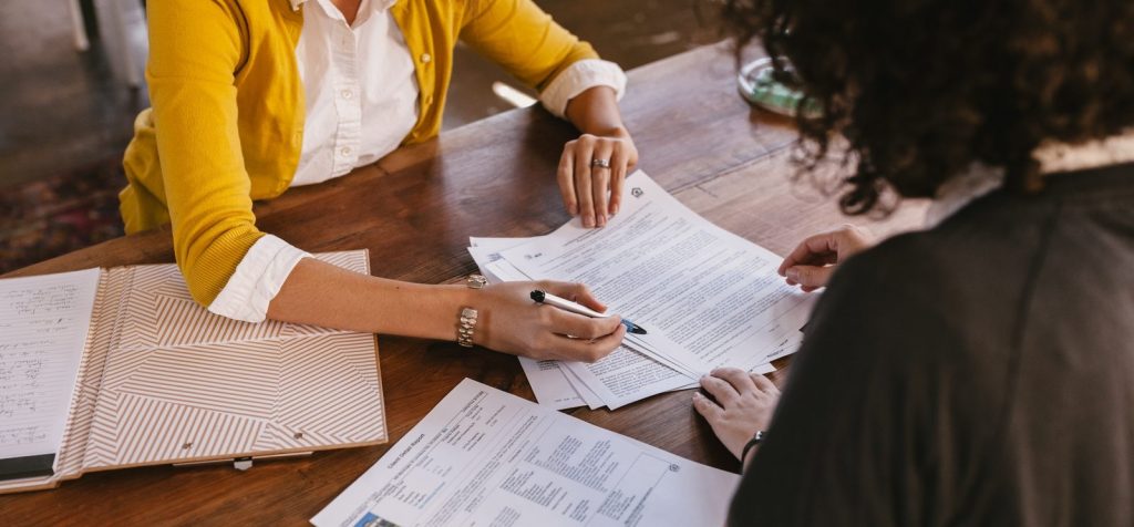 Deux personnes participant à une session de formation en entreprise autour d'une table avec des papiers et un stylo.