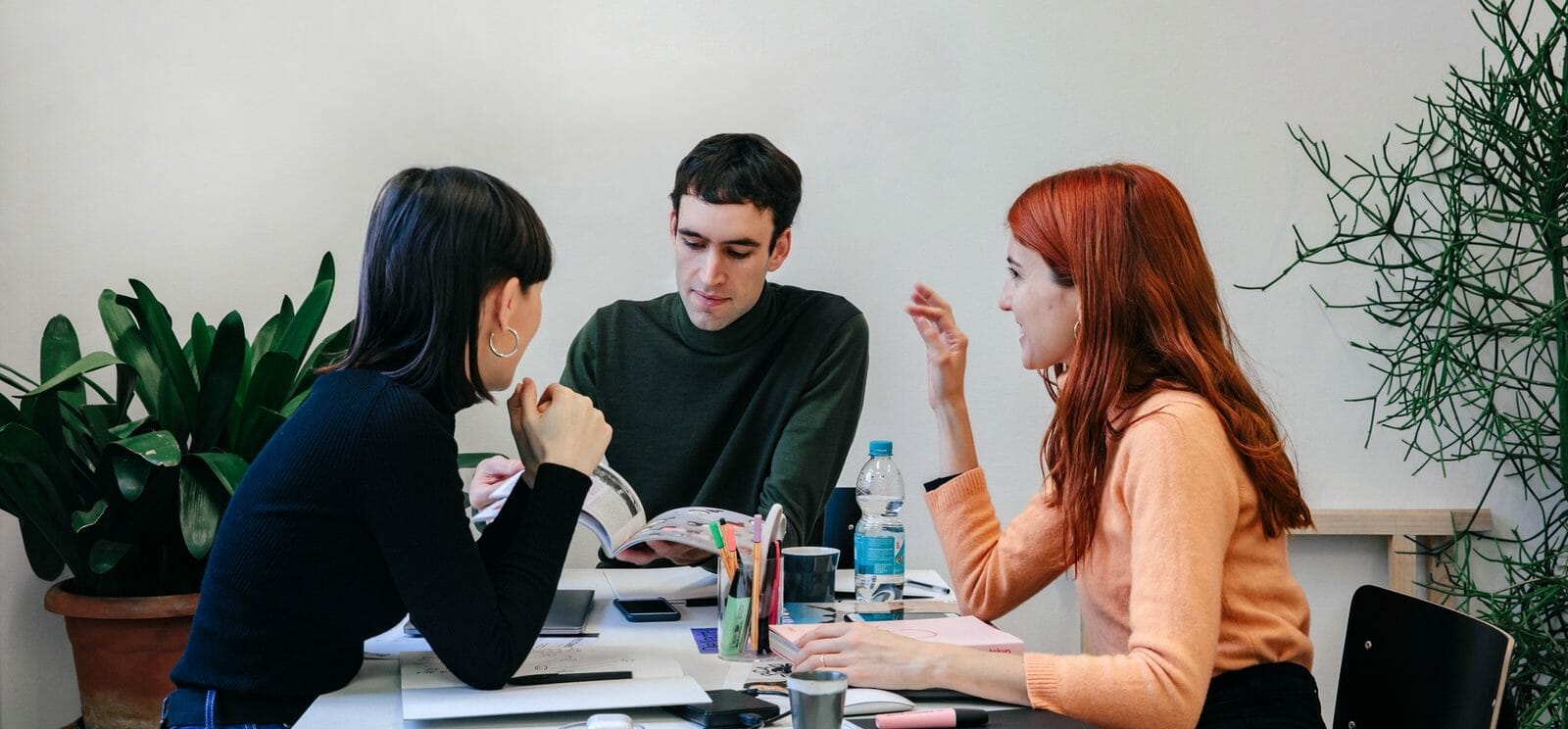 Eine Gruppe von Menschen übt Soft Skills, während sie an einem Tisch miteinander spricht.