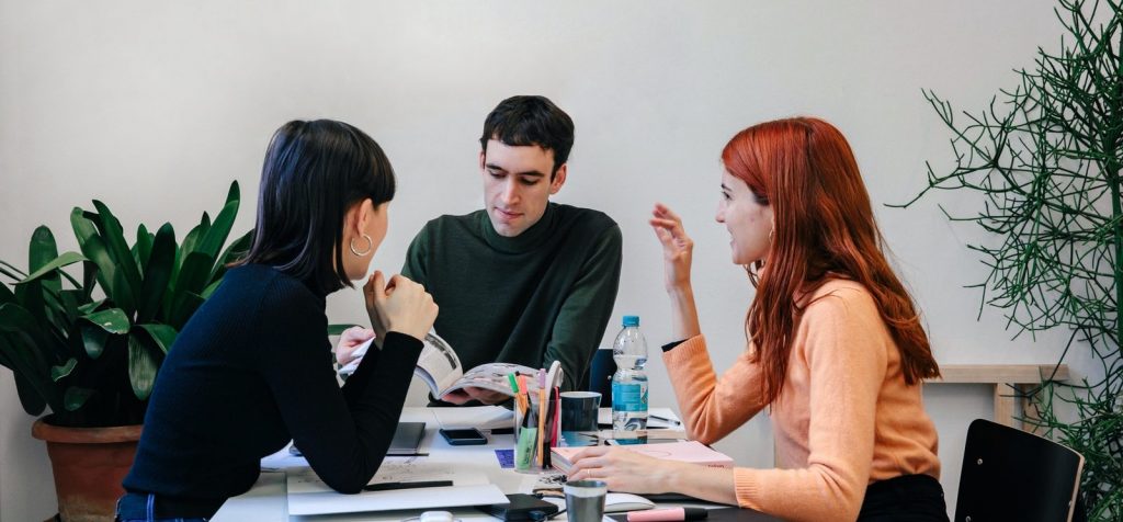 3 collègues utilisant des soft skills autour d'une table dans un environnement professionnel.